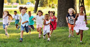 Children Running in the wooded grass during summer camp.