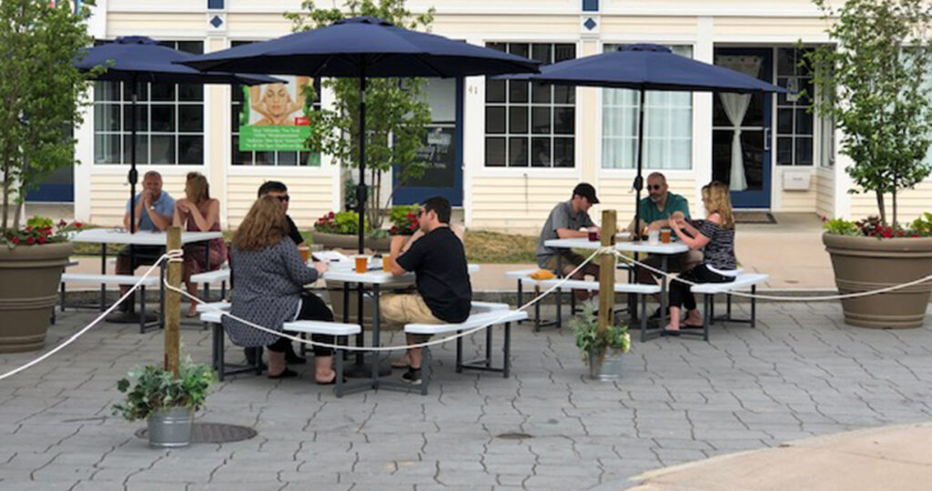 Patrons eating outside on restaurant patio at physically distant tables